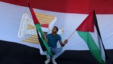 Seorang pria memegang bendera Palestina dengan latar bendera Mesir dalam perayaan setelah Hamas mencapai kesepakatan damai dengan Fatah. (REUTERS/Ibraheem Abu Mustafa).