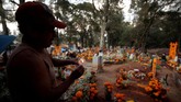 Masyarakat Meksiko dan Amerika Tengah mendatangi pemakaman dengan membawa berbagai barang saat Hari Orang Mati, mulai dari bunga, lilin, hingga barang khas mendiang kerabat mereka. (REUTERS/Alan Ortega)