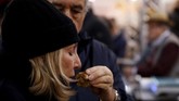 Salah satu highlight dari gelaran itu yakni lelang, yang tahun ini menjadi gelaran tahun ke-18, dengan keuntungan yang diperoleh diberikan untuk aksi amal. Seorang perempuan mencium wangi jamur truffle di pasar tradisional Alba. (REUTERS/ Stefano Rellandini)