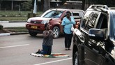 Seorang perempuan berlutut di atas bendera Zimbabwe di jalanan di Harare, Zimbabwe, pasca pengunduran diri Presiden Robert Mugabe, Selasa (21/11). (AFP PHOTO/MARCO LONGARI)