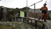 Seorang warga yang bekerja sebagai petugas kebersihan kota melintas di jembatan kawasan Kapuk Teko, Cengkareng, Jakarta Barat pada tanggal 1 Desember 2017. (Anadolu Agency/Eko Siswono Toyudho)