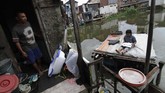 Seorang pria memerhatikan anaknya yang sedang belajar di atas rakit di kawasan Kampung Apung.(Anadolu Agency/Eko Siswono Toyudho)
