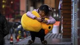 Seorang perempuan di Shanghai, China, berjongkok dengan mainan bebek di pangkuannya, sembari menggunakan telepon genggam. (AFP/CHANDAN KHANNA)