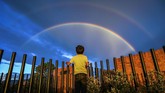 Seorang bocah melihat pelangi ketika matahari terbenam di kota Bogota, Kolombia. Pelangi pernah hadir dalam puisi Pablo Neruda.
