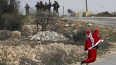Selain di Gaza, para demonstran berkostum Sinterklas juga beraksi di Ramallah, Tepi Barat. Mereka melemparkan batu ke arah militer Israel. (Reuters/Mohamad Torokman)