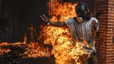 Seorang demonstran anti-pemerintah Presiden Nicolas Maduro tersambar api setelah sebuah tangki gas motor polisi meledak dalam bentrokan di Caracas, Venezuela 3 Mei 2017. (AFP PHOTO/JUAN BARRETO)