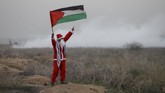 Seorang demonstran berpakaian Santa Claus mengibarkan bendera Palestina dalam aksi protes melawan keputusan Presiden Amerika Serikat Donald Trump untuk mengakui Yerusalem sebagai Ibu Kota Israel, foto diambil di Jalur Gaza, 19 Desember 2017. (REUTERS/Mohammed Salem)