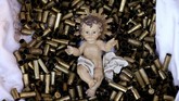Patung bayi Yesus terbaring di kasur yang terbuat dari selongsong-selongsong peluru di Basiliki Santa Francis di Assisi, Italia. Total 445 selongsong peluru menjadi simbol jumlah pendeta, biarawati dan biarawan yang terbunuh sejak tahun 2000 untuk membela keyakinan mereka. (Reuters/Alessandro Bianchi)