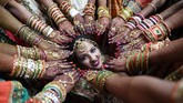 Seorang pengantin perempuan di India berpose di sebuah pernikahan massal sementara yang lain menunjukkan tangan yang sudah dihiasi. Pernikahan ini digelar di Surat, 270 kilometer dari Ahmedabad. Total 251 pasangan menikah pada acara yang digelar badan amal grup PP Savani dan Movaliya. (AFP/Sam Panthaky)
