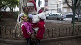 Seorang yang berkostum Sinterklas berpose dengan seorang gadis kecil dalam sebuah acara yang merayakan akhir dari musim Natal di kota Rio de Janeiro, Brasil. Perayaan ini selalu digelar setiap tahun, satu hari setelah Natal, oleh sekolah yang mendidik para Sinterklas 'profesional'. (AFP/Mauro Pimentel)