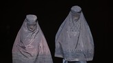 Dua perempuan Afghanistan mengenakan burka berjalan meninggalkan toko di sebuah pasar di Mazar-i-Sharif. (AFP PHOTO / FARSHAD USYAN)