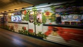 Para penumpang duduk di dekat kereta metro yang berhiaskan ornamen tahun baru di Moskow. (AFP PHOTO / Yuri KADOBNOV)
