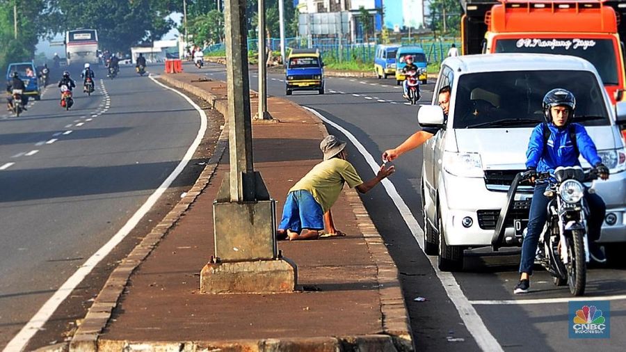 Seorang pengemis menerima uang dari pengendara mobil roda empat
