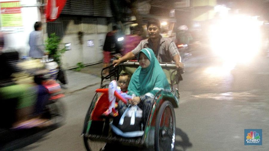 Seorang pengayuh becak mengangkut penumpang di kawasan Pasar Warakas, Tanjung Priok, Jakarta, Selasa (16/1/2018) malam. Gubernur DKI Jakarta Anies Baswedan mengatakan untuk merealisasikan wacana pengoperasian becak akan disusun lebih dulu aturannya. Dalam aturan yang akan dibuat, tertuang ketentuan seperti zona pengoperasian becak, sampai sanksi bila terjadi pelanggaran.