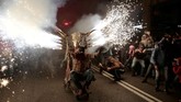 Perayaan Correfocs dilakukan dengan mengenakan kostum. Para peserta mengenakan kostum berbentuk iblis yang melambangkan kejahatan. (REUTERS/Enrique Calvo)