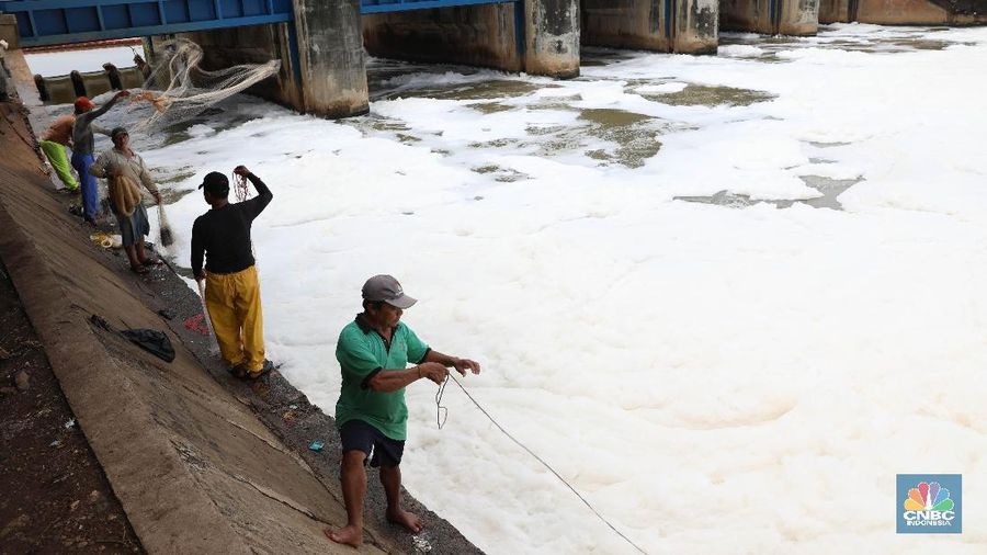 Sejumlah warga banyak menghabiskan waktu mereka dengan mencari ikan menggunakan jala di Pintu Air Weir 3 Marunda dengan kondisi air berbusa limbah rumah tangga.