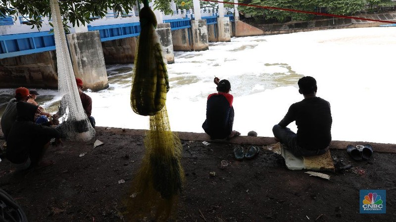 Sejumlah warga banyak menghabiskan waktu mereka dengan mencari ikan menggunakan jala di Pintu Air Weir 3 Marunda dengan kondisi air berbusa limbah rumah tangga.