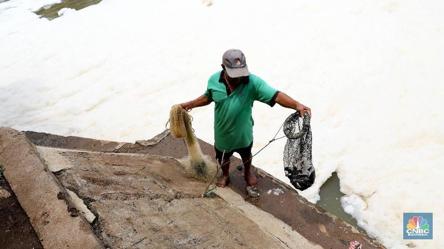 Sejumlah warga banyak menghabiskan waktu mereka dengan mencari ikan menggunakan jala di Pintu Air Weir 3 Marunda dengan kondisi air berbusa limbah rumah tangga.