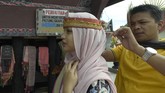 Turis asal Malaysia memakai ikat kepala wanita khas Batak Toba sebelum tampil menari Tortor bersama Sigale Gale.