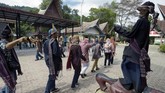 Sejumlah turis menari membentuk lingkaran. Diiringi musik Sordan dan Gondang Sabangunan, mereka menari Tortor di depan Sigale Gale.