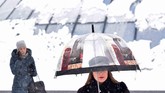 Seorang perempuan berjalan menggunakan payung di pusat kota Kiev, Ukraina, ketika terjadi hujan salju yang tebal. (AFP/ Sergei SUPINSKY)