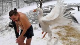 Seekor angsa menyerang seorang kristen ortodoks ketika meninggalkan danau air es usai merayakan hari Epifani Ortodoks di Kiev, Ukraina. (AFP/ Sergei SUPINSKY)