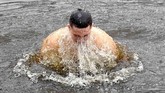 Seorang kristen ortodoks mencemplungkan diri di air es di sebuah danau ketika merayakan hari Epifani Ortodoks di Kiev, Ukraina. (AFP/ Sergei SUPINSKY)