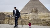 Perempuan India yang merupakan perempuan terpendek di dunia, Jyoti Amge, berpose bersama pria tertinggi di dunia, Sultan Kosen dari Turki, dengan latar belakang Piramida Giza, Sphinkx, dan juga Piramida Khafre. (AFP PHOTO / STRINGER)