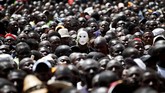 Seorang pria mengenakan topeng berbaur di antara pendukung Raila Odinga lainnya ketika Odinga disumpah jabatan di Nairobi menjadi pemimpin negara Kenya. (REUTERS/Baz Ratner)