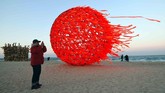 Seorang pria mengambil foto instalasi seni matahari di pantai Gyeongpo di Gangneung, Korea Selatan. Saat ini Korea Selatan sendiri sedang menyiapkan diri untuk pesta Olimpiade Musim Dingin 2018. (AFP PHOTO / JUNG Yeon-Je)