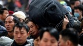 Kerumunan manusia memanggul koper dan kardus mi instan terlihat berjejalan memasuki stasiun di Beijing, menunggu kereta yang akan membawa mereka ke kampung halaman. (China Daily via Reuters)