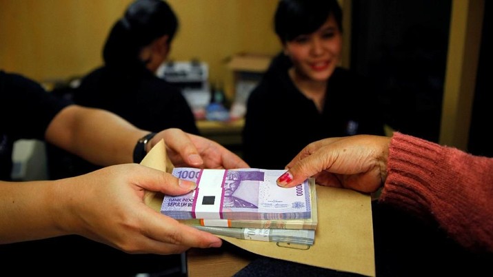 FILE PHOTO: A woman holds Indonesian rupiah banknotes at a Bank Negara Indonesia (BNI) mobile bank in Jakarta July 15, 2013.   REUTERS/Beawiharta/File Photo