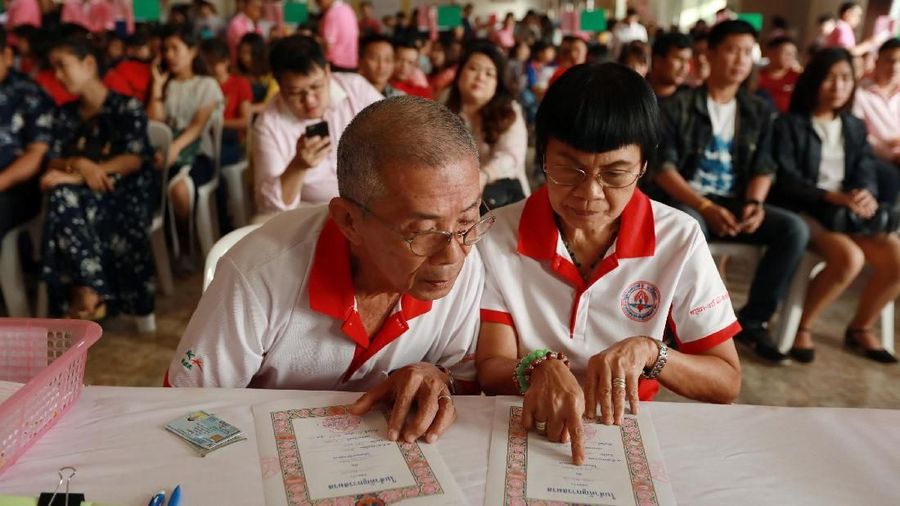 Groom Mana Pienthawornkij, 76 dan mempelai wanita Kaset Saiyalangka, 62, menandatangani sertifikat saat perayaan Hari Valentine di kantor Pos Bangrak di Bangkok, Thailand, 14 Februari 2018. REUTERS / Soe Zeya Tun
