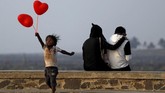 Seorang anak melompat setelah berusaha menjajakan balon berbentuk hati pada pasangan yang sedang berdusaan di hari Valentine di Mumbai, India. (REUTERS/Francis Mascarenhas)