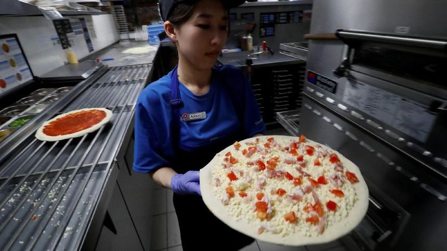 FILE PHOTO: A staff member makes a pizza at a Domino's Pizza restaurant in Moscow, Russia, July 14, 2017. Picture taken July 14, 2017. REUTERS/Sergei Karpukhin/File Photo GLOBAL BUSINESS WEEK AHEAD - SEARCH GLOBAL BUSINESS 19 FEB FOR ALL IMAGES