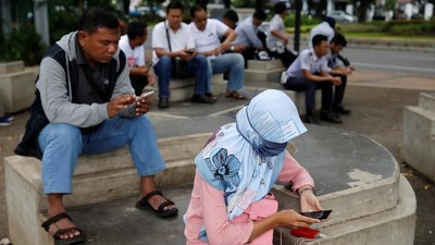 People use smartphones on a sidewalk in Jakarta, Indonesia, February 14, 2018. Picture taken February 14, 2018. REUTERS/Beawiharta