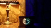 Kanan: Jam dengan bahan kaca uranium buatan 1950 berpendar dalam sinar ultraviolet. Kiri: dalam cahaya normal. Sejumlah barang antik dari kaca uranium ini milik Peter Marti dan Markus Berner yang menjualnya di rumah mereka di Wangen an der Aere, Swiss. (REUTERS/Stefan Wermuth)