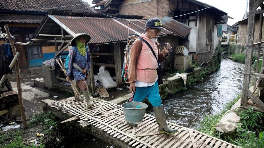 Petani berjalan di atas sungai dekat Danau Cisanti, sumber utama sungai Citarum, di pegunungan selatan Bandung, di desa Tarumajaya, provinsi Jawa Barat, Indonesia, 24 Februari 2018. REUTERS / Darren Whiteside