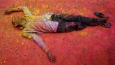 Seorang penganut agama Hindu, dengan tubuh yang diselimuti serbuk warna, beristirahat di jalan. Ia sedang mengikuti perayaan Holi di Kolkata, India. (REUTERS/Rupak De Chowdhuri)