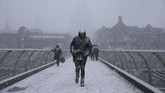 Para pejalan kaki melintasi jembatan millennium di tengah-tengah hujan badai salju di London. Pada pekan ini, Eropa diterpa suhu dingin karena pengaruh cuaca Siberia sehingga para pejalan pun terkena sakit dan beberapa di antaranya meninggal dunia. (AFP PHOTO / Daniel LEAL-OLIVAS)