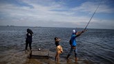 Tiga orang anak bermain di peissir saat air laut mulai naik di Kali Adem, Jakarta, 4 Januari 2018. Abrasi dari air laut yang naik adalah ancaman yang bisa membuat Jakarta 'tenggelam'. (REUTERS/Beawiharta)