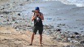 Foto ini diambil pada 19 Desember 2017 saat seorang turis asing sedang berdiri di antara sampah plastik berserak di pantai Kuta, Bali. Belakangan pariwisata Bali kembali dihantam isu sampah setelah seorang turis asal Inggris merekam sampah plastik saat menyelam di kawasan Nusa Penida. (AFP PHOTO / SONNY TUMBELAKA)