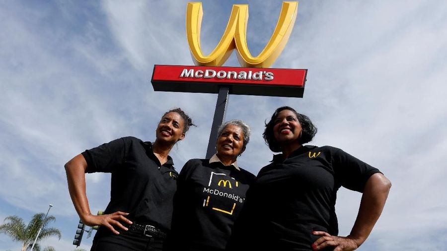 Restaurant owner Patricia Williams (C) and her daughters Kerri-Harper-Howie (L) and Nicole Enearu pose for a picture in front of the McDonald's iconic 'M' logo after Mcdonald's turned the sign upside down in honour of International Women's Day in Lynwood, California, U.S., March 8, 2018. REUTERS/Mike Blake