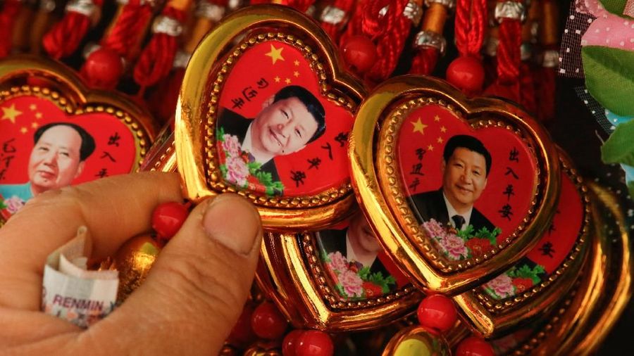 FILE PHOTO: A woman picks a souvenir necklace with a portrait of Chinese President Xi Jinping from a selection that also includes necklaces featuring late Chinese Chairman Mao Zedong at a stall in Tiananmen Square in Beijing, China, February 26, 2018. REUTERS/Thomas Peter/File Photo NO RESALES. NO ARCHIVES
