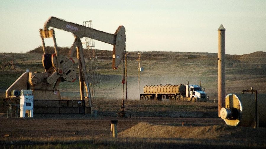 Truk pengangkut truk melewati sumur minyak di Fort Berthold Indian Reservation di North Dakota, A.S., 1 November 2014. REUTERS / Andrew Cullen / File Photo