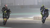 Pebalap Tech3 Yamaha Johann Zarco (kiri) dan pebalap Movistar Yamaha Valentino Rossi melakukan wheelie usai babak kualifikasi MotoGP Qatar. (AFP PHOTO / KARIM JAAFAR)