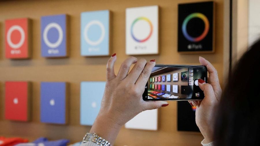 FILE PHOTO: A visitor uses her iPhone X to take a photo of Apple Park t-shirts at the new Apple Visitor Center in Cupertino, California November 17, 2017. REUTERS/Elijah Nouvelage/File Photo