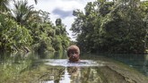 Seorang anak perempuan Papua berenang di Kali Biru yang berada di Lansekap wilayah adat Knasaimos, Kabupaten Sorong Selatan, Papua Barat. (Greenpeace/Jurnasyanto Sukarno)