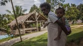 Seorang nenek sedang menggendong cucunya di Kampung Sira. Masyarakat kampung Sira yang juga berada dalam lansekap wilayah adat Knasaimos menolak masuknya persuahaan besar masuk seperti perusahaan kelapa sawit dan pembalakan hutan. (Greenpeace/Jurnasyanto Sukarno)