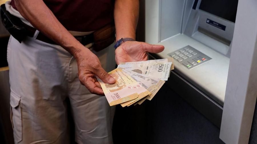 Seorang pria menunjukkan catatan Bolivar setelah menariknya dari mesin kasir otomatis (ATM) di Caracas, Venezuela 23 Maret 2018. REUTERS / Marco Bello
